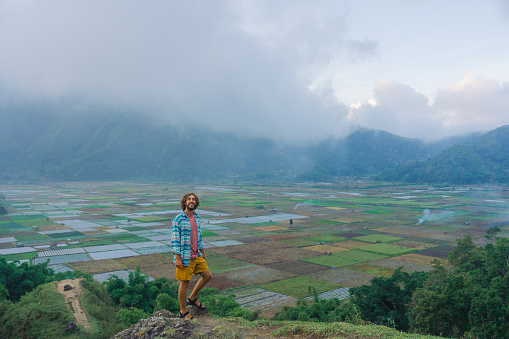 Man standing on mountains and looking at Sembalun village  and agricultural fields in Lombok