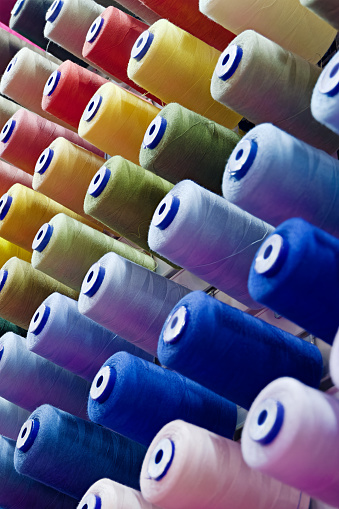 Assorted spools of multi-coloured cotton threads, abstract textile industry background