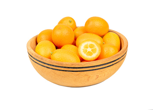 Wooden bowl full of fresh kumquat fruit isolated on white background