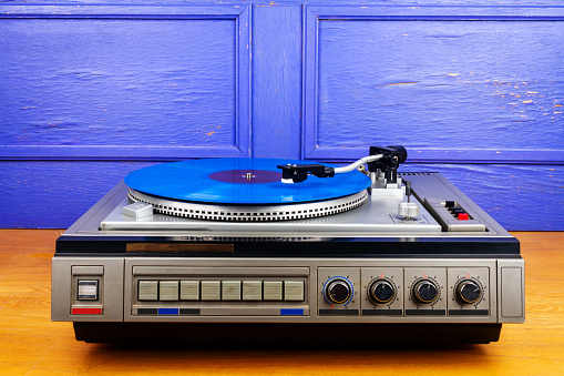 Vintage turntable vinyl record player with blue vinyl on a table