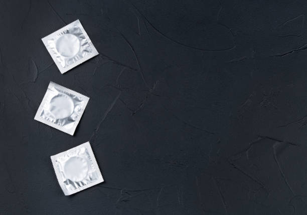 three condoms in a pack on a dark background - contraceptive sex education birth control pill condom 뉴스 사진 이미지