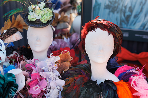 There are many different hats with feathers, flowers at the exhibition