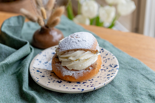 Typical Swedish semla with sweet cream on te blue textile.