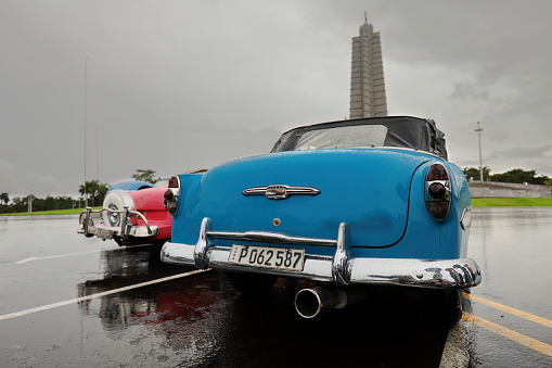 Havana, Cuba-October 7, 2019: American classic convertible cars (R - L), blue Chevrolet Bel Air 1953-pink Ford Fairlane Sunliner 1956-blue Chevrolet Styleline DeLuxe 1950, parked on Revolution Square.