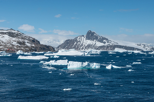 Seascape with floating ice on the sea, mountains in the background. blue sky. Travel image of Cierva Cove, Antarctica.