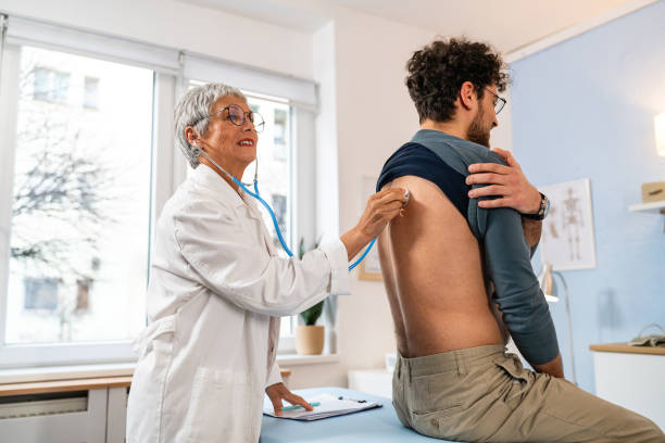 istock Senior Caucasian female doctor, examining male patient's lungs while using stethoscope 2089253371