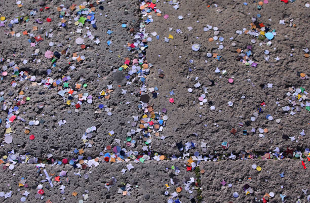 Close up of small multicolored plastic debris scattered on a rough ground surface, showing detailed texture and variety of plastic fragments in assorted shapes and colors