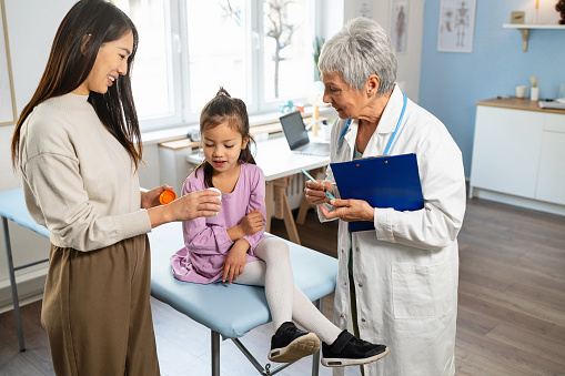 Japanese  girl at the senior female Caucasian pediatrician with her mother, for an annual medical check-up.