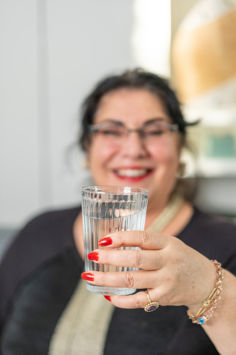 Cheerful old woman drinking clean plain water daily to live healthy and beautiful