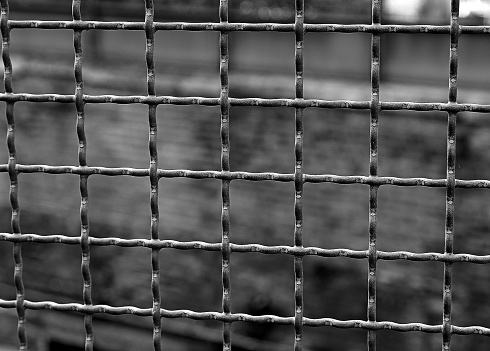 Iron bars separate the prison from the wall in the background with very dark tones for a dramatic black and white effect
