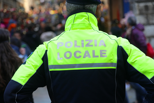 Italian city with policeman on guard with text on uniform meaning Local Police during patrolling