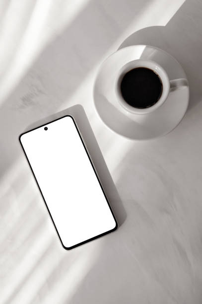 istock Smartphone with empty screen mock up and cup of hot coffee drink on marble neutral beige background with aesthetic natural sun light shadows, flat lay, elegant business branding template 2089342909