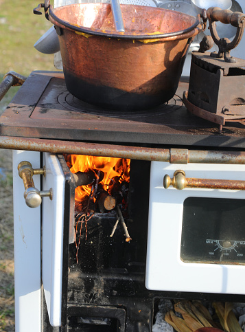 Old wood-fired kitchen range with a lit fire and a copper cauldron above for cooking