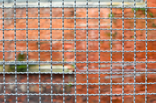 metallic border separation fence and the brick wall of the penitentiary out of focus in background