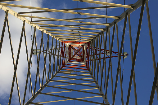 pylon with high voltage cables for the transport of electricity and white clouds on the sky