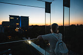 adult woman standing on terrace or balcony and looking at evening sunset