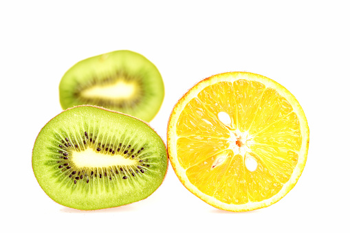 Fruitarian diet lifestyle. Halves of kiwi fruit and orange isolated on white background with selective focus, close up.