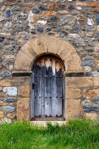 Door aged by time under the bell tower of the Nuestra Señora del Rosario church, Riaño.