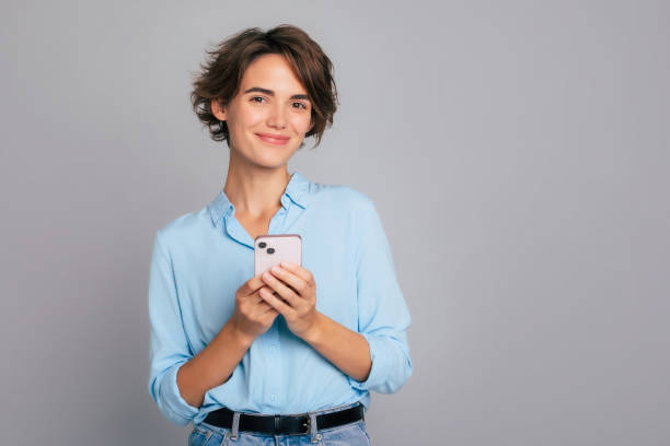 istock Excited confident businesswoman in smart casual in studio while using smartphone and working. Young female using apps on cell phones, reading news, fast connection, searching, bet, surfing network 2089430352