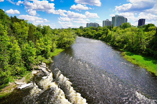 Beautiful panorama of Rideau River flowing along tree lined shores with Ottawa city's downtown visible in the far distance on a bright summer day at Ottawa,Ontario,Canada