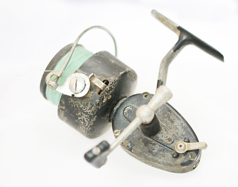 a very old spincast fishing reel on a white background