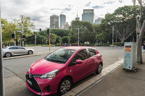 Sydney, NSW, Australia, February 20th 2024. Pink Toyota Yaris parked on a street with an urban skyline in the background.