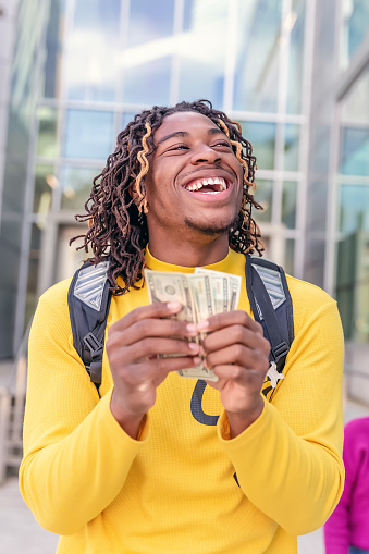 Young  student holding money smiling