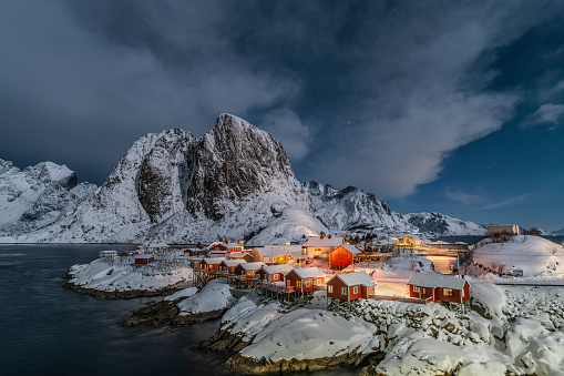 Traditional norwegian fishing village Hamnoy in the beautiful snow covered winter landscape of the Lofoten Islands at winter time. Festhelltinden mountain in the background. Northern Norway in Scandinavia - Europe