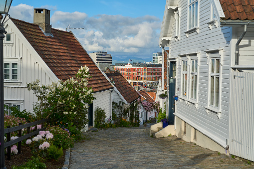 Stavanger, Norway - 05 29 2022: historic street with beautiful traditional white wooden houses in Gamle Stavanger in Rogaland, Norway, sunny day