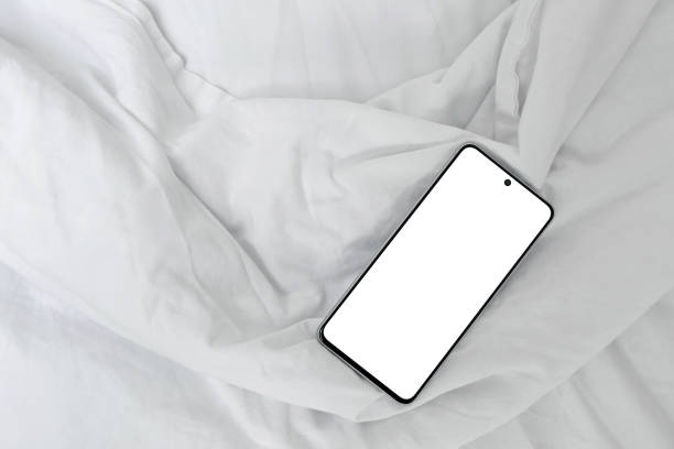 istock Mobile phone with blank screen mockup on bed with white crumpled cotton sheet and blanket background, lifestyle home interior, minimal business branding template 2089501986
