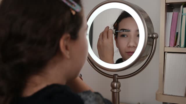 Teenager girl putting mascara on eyebrows