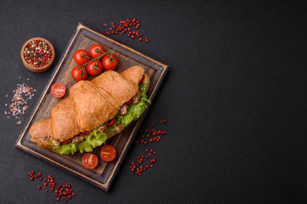 delicious fresh crispy croissant with chicken or beef meat, lettuce, tomatoes, spices and sauce - bun salad ham rolled up photos et images de collection