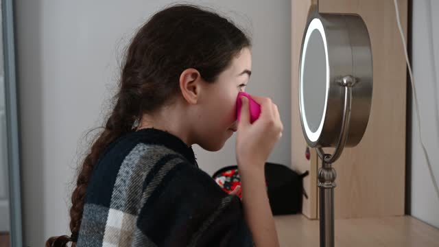 Teenager girl putting make-up with sponge