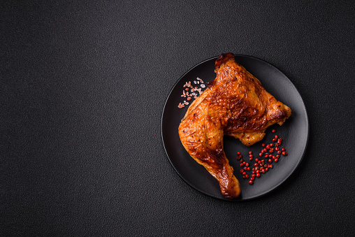 Delicious grilled chicken leg or quarter with salt and spices on dark concrete background
