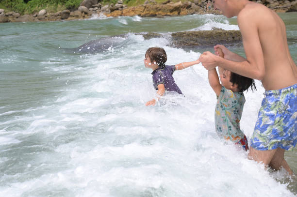 Playful Caucasian boy running into sea and playing with waves, during sea vacation