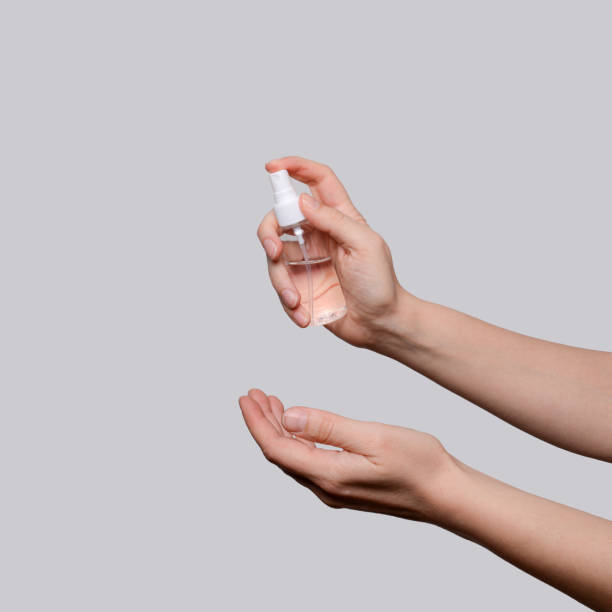 istock Female hands using hand sanitizer spray dispenser over light grey background 2089525211