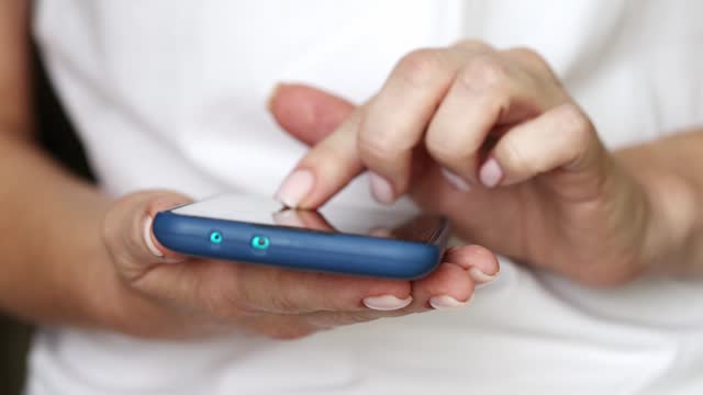 Woman typing message on a smartphone. Closeup of female hands browsing the device.