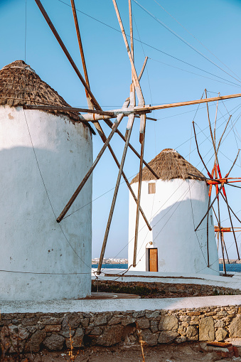 Landscape view of traditional old white windmills in Mikonos town (Chora), Mykonos island, Cyclades, Greece at sunset time with clear sunny sky.