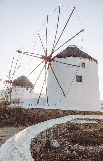 Landscape view of traditional old white windmills in Mikonos town (Chora), Mykonos island, Cyclades, Greece at sunset time with clear sunny sky.