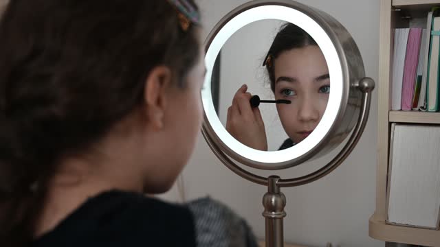 Teenager girl putting mascara on eyelashes