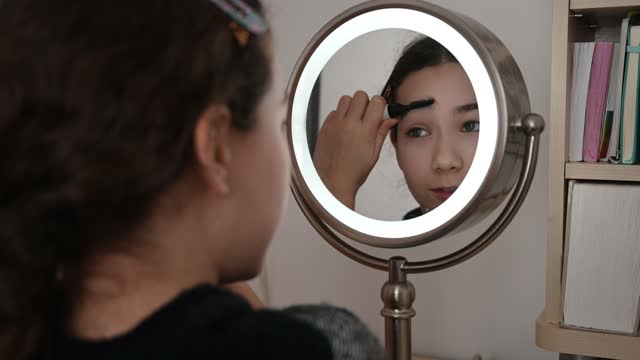 Teenager girl combing eyebrows
