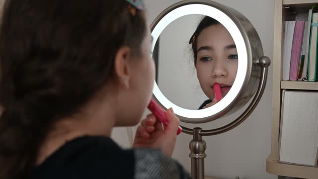Teenager girl putting lipstick