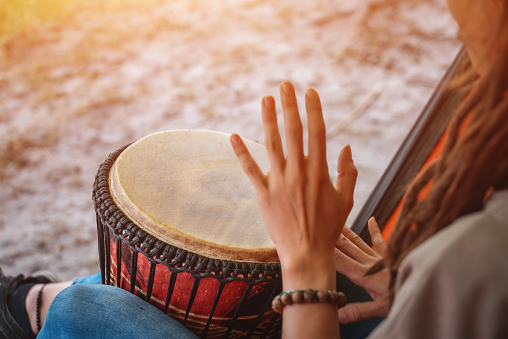 person with dreadlocks play tribal reggae at small African hand drum djembe. High quality picture