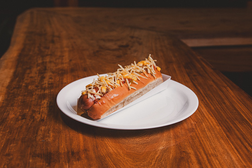Hot dog with french fries on a wooden table.