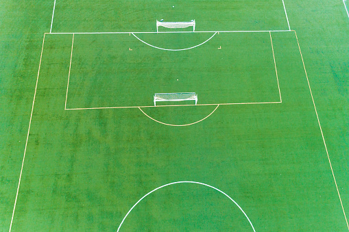 A soccer field with two goals and a bench. The field is green and well maintained. Concept of sportsmanship and teamwork