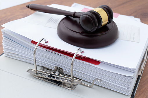 On the table is a judge's wooden gavel and document with the inscription covid -19. Coronavirus pandemic litigation concept