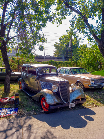 Remedios de Escalada, Argentina - Feb 11, 2024: Old aged 1934 Ford V8 model 40 coupe 5 window under the trees at a classic car show in a park. Copy space