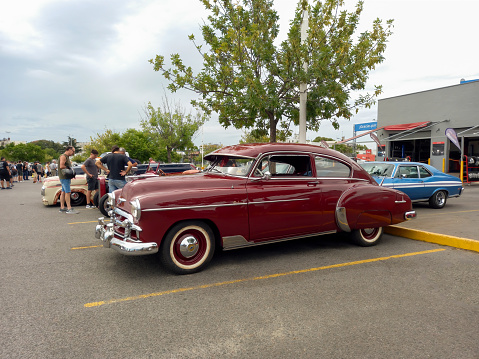 Buenos Aires, Argentina - Feb 25, 2024: Old red shiny 1949 Chevrolet Styleline two door sedan at a classic car show in a parking lot. Side view. Copy space