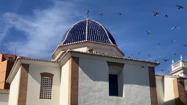 Pigeons flying away from church rooftop