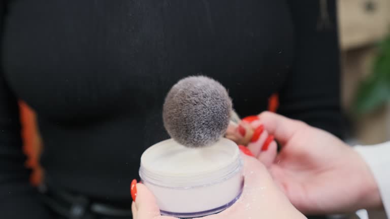 Makeup artist removes excess powder off brush before applying